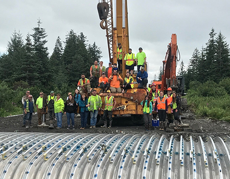 Project partners and contractors celebrating together after successfully laying in a new fish passage culvert near Cordova emPhoto source Copper River Watershed Projectem