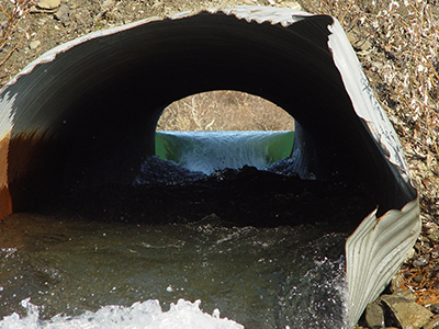 This perched pipe is located on the Taylor Highway and is clearly too small for the size of the stream it is located on There are hydraulic jumps both at the outlet and inlet of the culvert and swift velocities inside the pipe making it difficult for fish to pass through Note the rust lines in the pipe indicating these are not the highest flows for this system