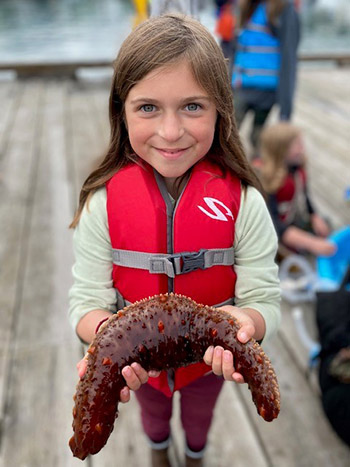 Mia Wood holds a sea cucumber brought up form the harbor by science divers Kellii WoodADFampG