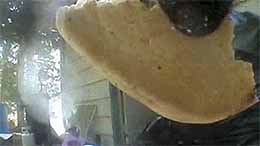 A still image captured from video recorded by a cameracollared black bear That39s a piece of food pizza perhaps  pulled from a trash can and the bear39s chin at the top right