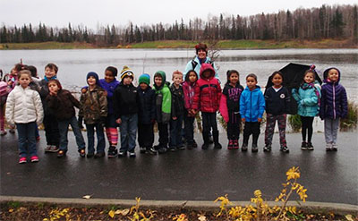First graders at Campbell Elementary in Anchorage prepare to set up a trail camera at Taku Lake