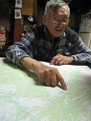 A Nulato resident looks over a map and notes a location on the Yukon River