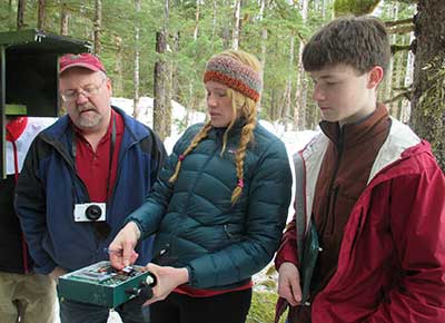 Biologist Michael Kohan center shows volunteers in Gustavus how the bat detector works