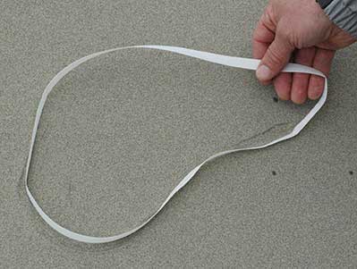 A white plastic packing band on a beach Cut all loops or bands and dispose of them properly to keep marine debris out of the oceanPhoto by Kim RaumSuryan