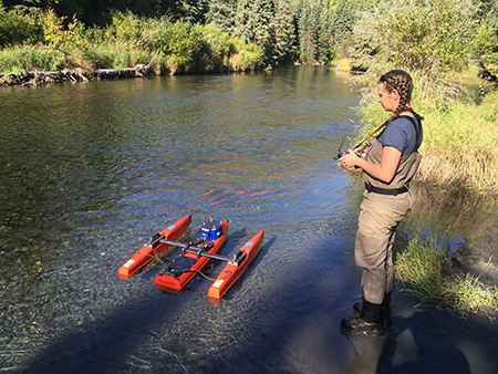 Coauthor Leah Ellis operates an ADCP mounted on a remotecontrolled boat known as a Qboat The Qboat was used at this site to avoid wading across the stream and disturbing salmon redds Photo Credit Instream Flow Program
