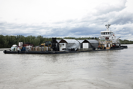 Yearling bison in specialized shipping containers leaving Nenana on the Tanana River by barge July 2022
