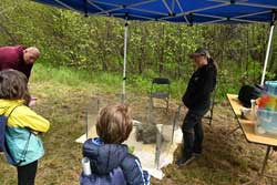 Group of people standing around a woman with a porcupine nearby